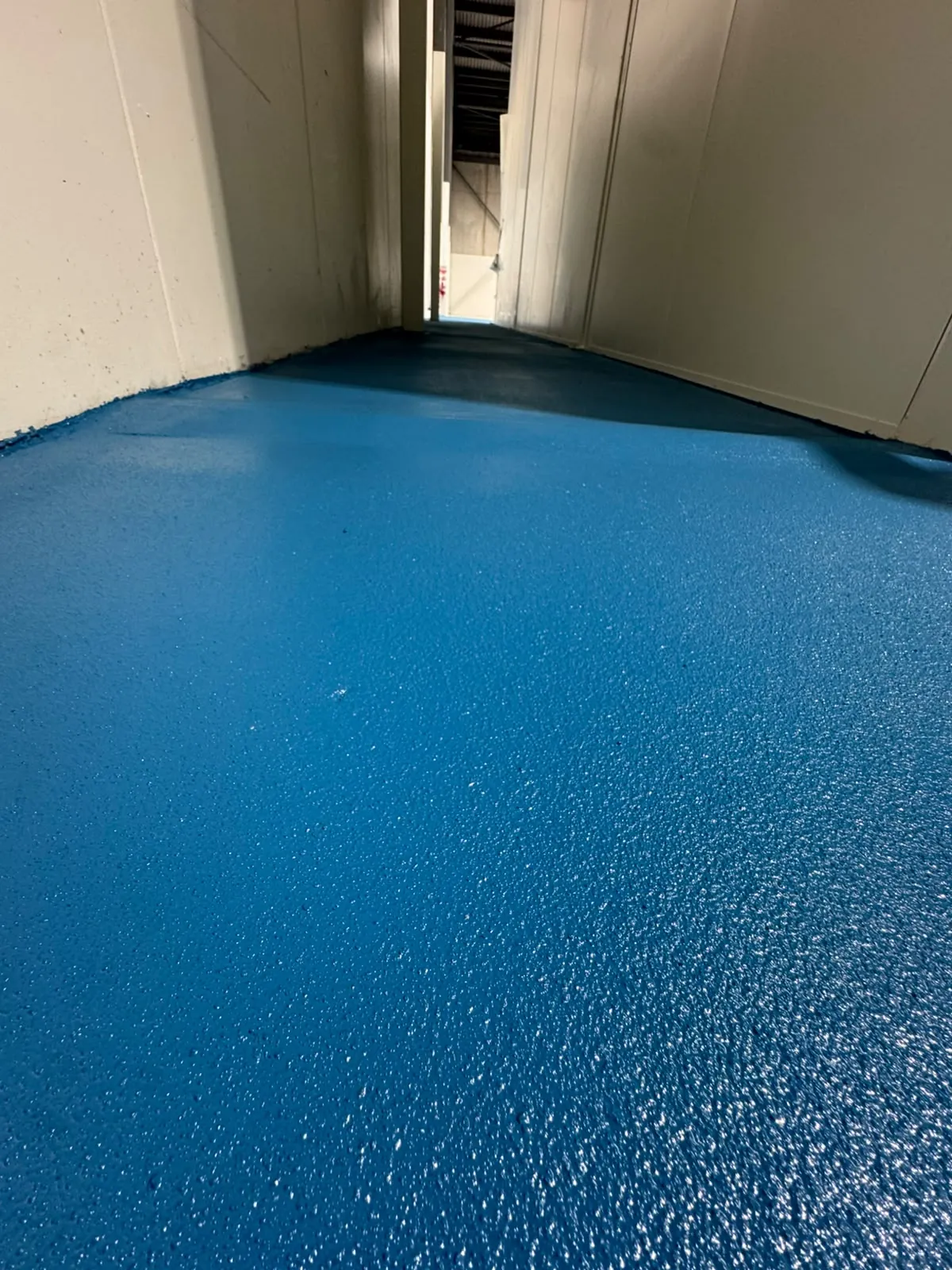 Blue epoxy floor coating in a narrow room